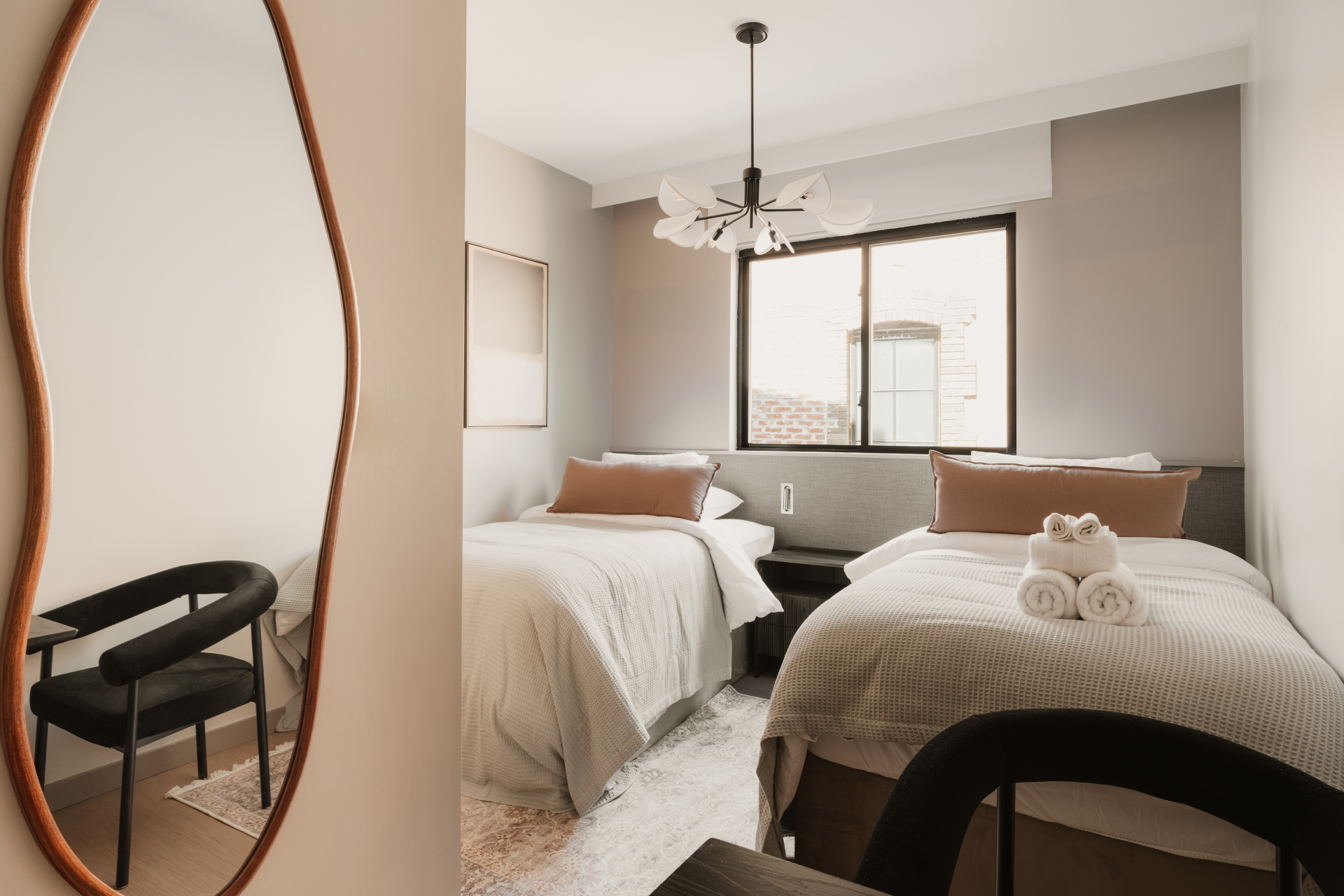 Guest room with two beds, an accent chair and a full-length mirror