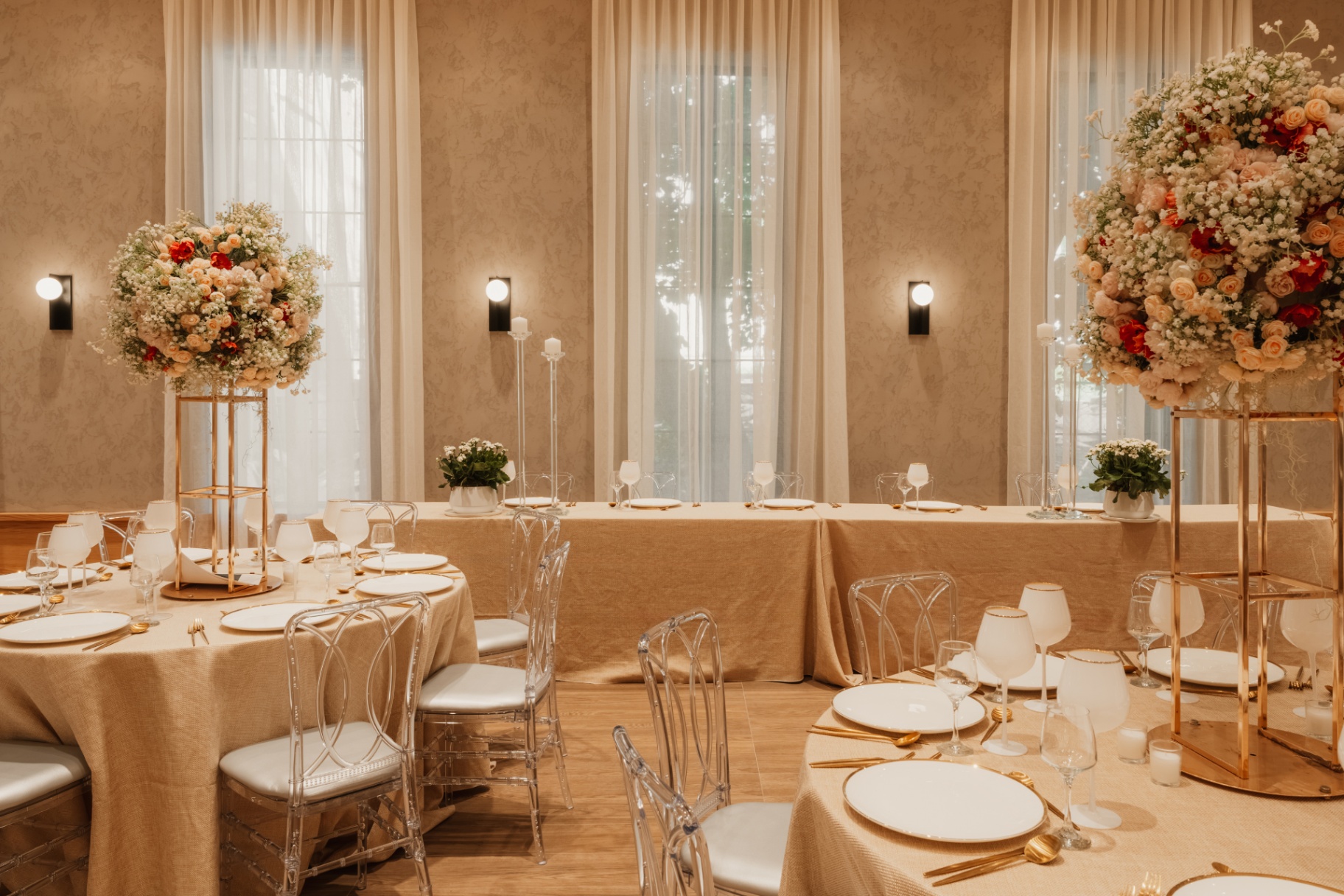 Head table with tall floral arrangements and gold accents in the event room