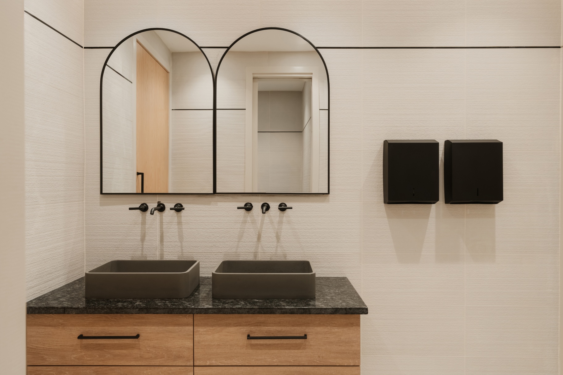 Double vanity with arched mirrors and matte black fixtures