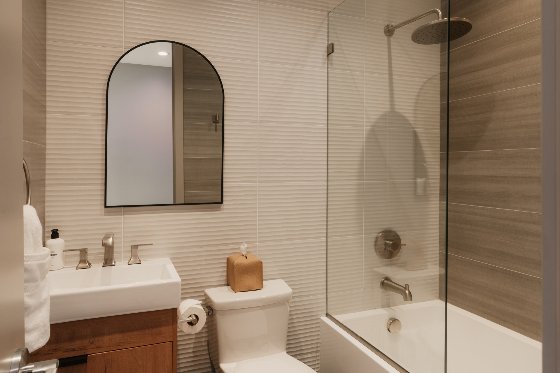 Bathroom with a tub and shower combination and arched mirror