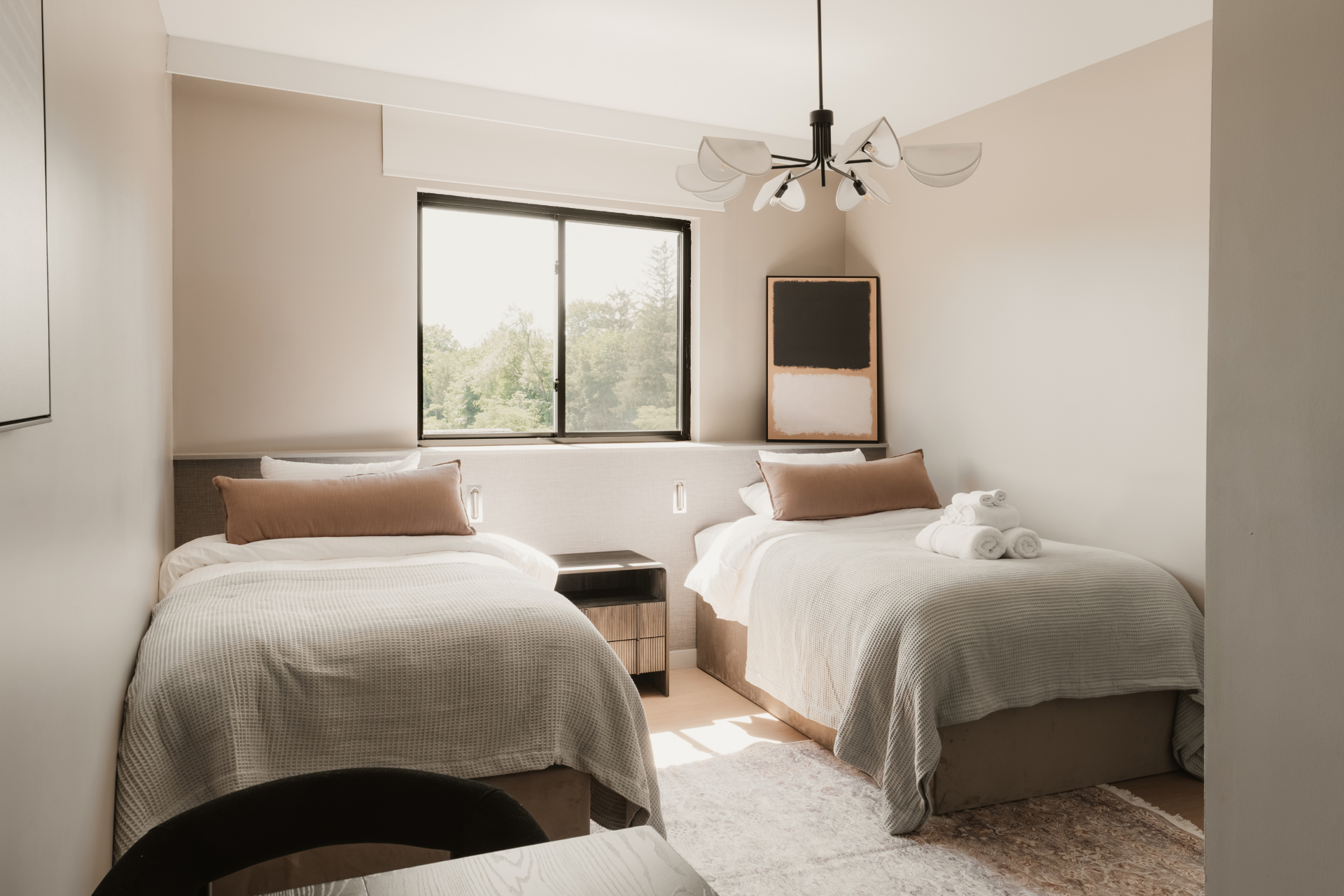 Guest room with two beds, a chandelier and a window over the trees