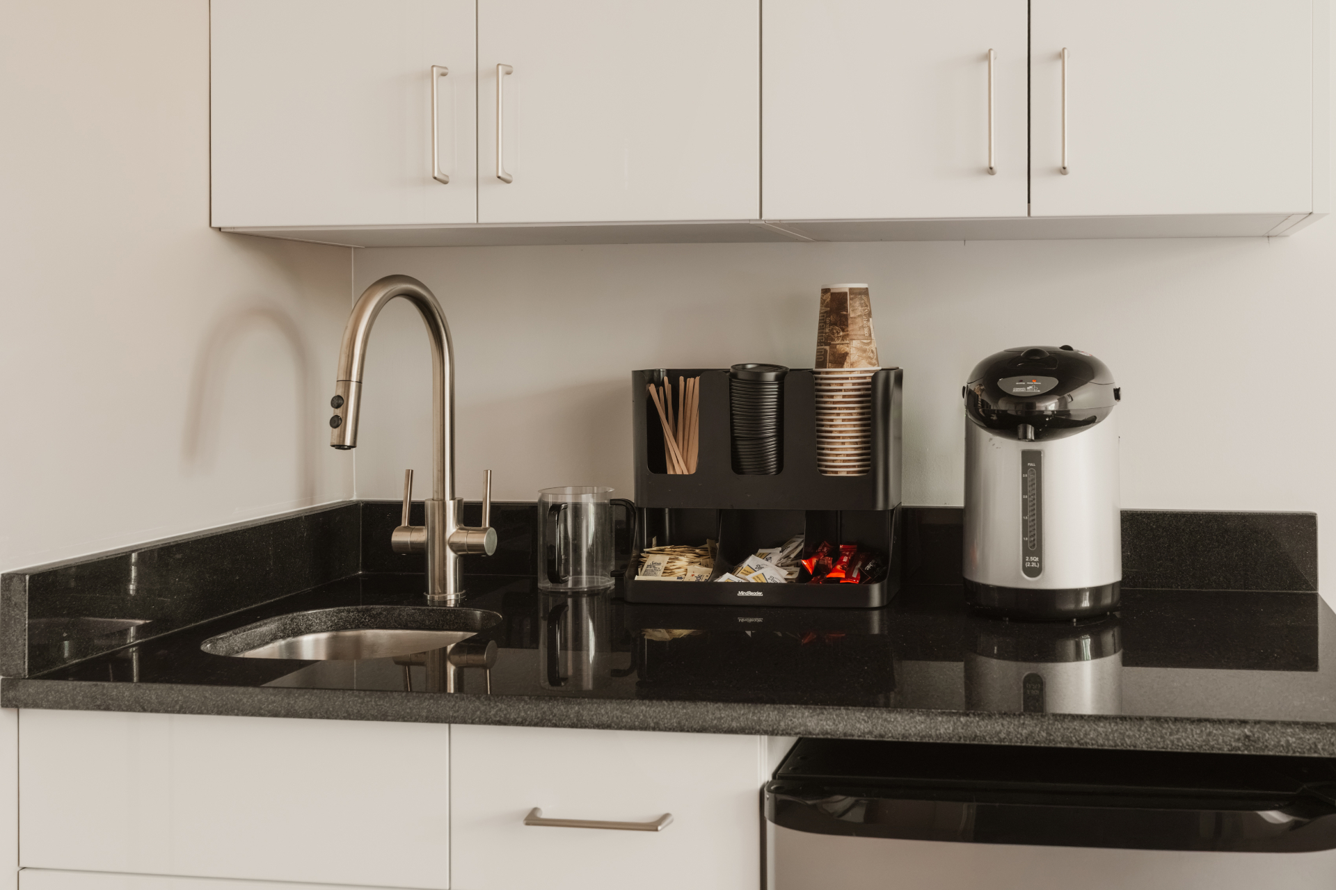 Kitchenette with black granite counter, sink and coffee station