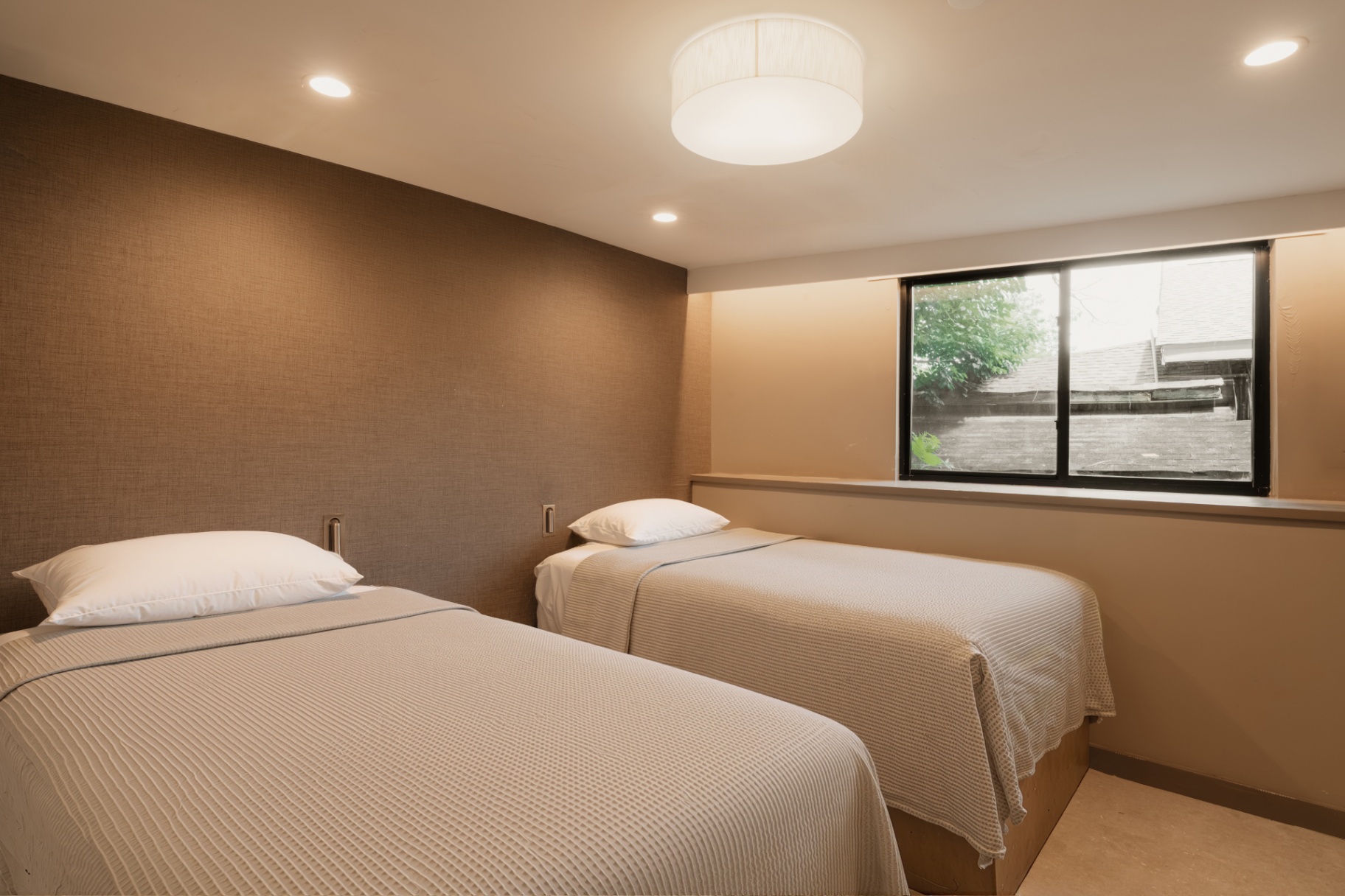 Single bed guest room with soft lighting and a window