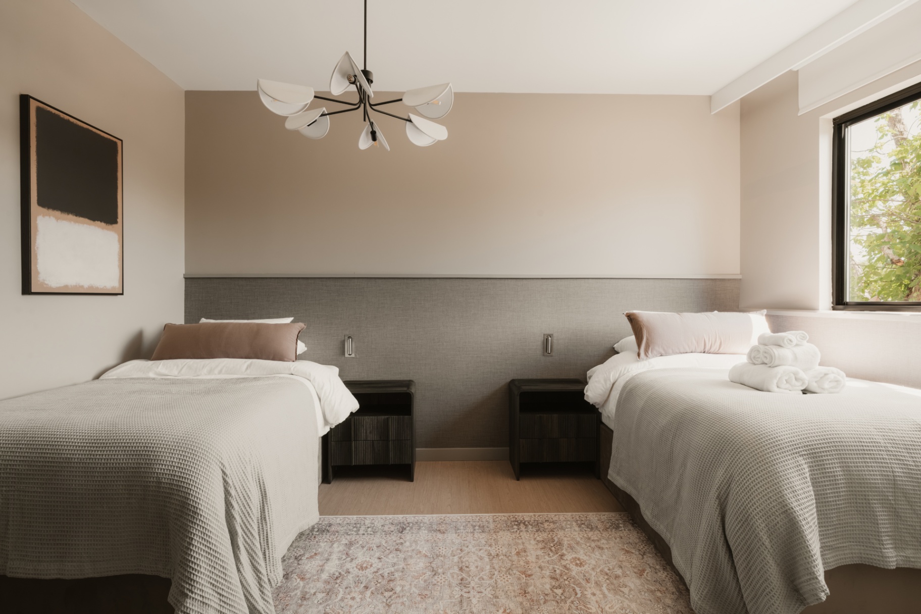 Guest room with twin beds, rolled towels and a soft neutral palette