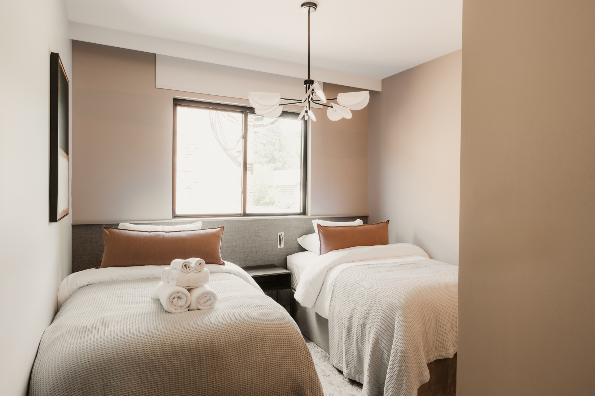 Twin beds under a chandelier in a bright guest room