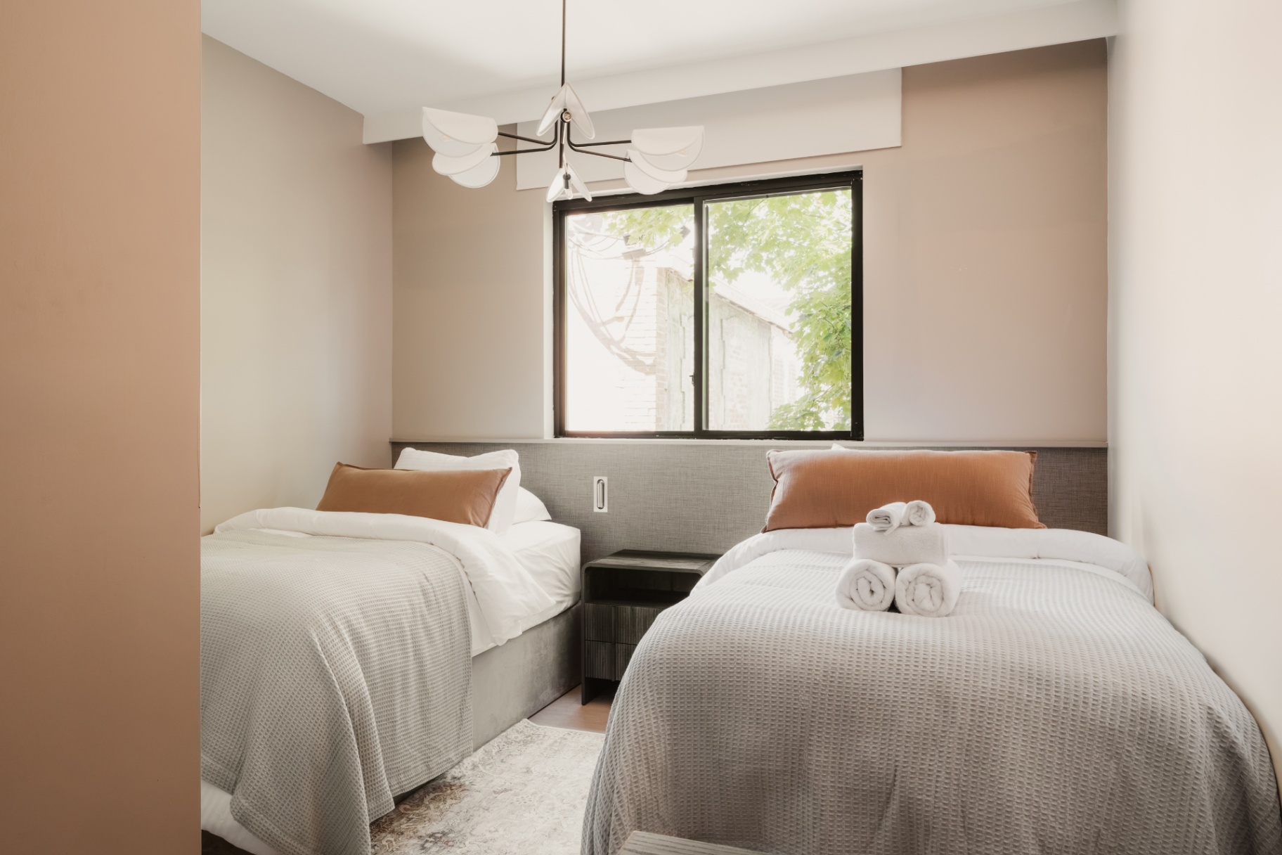 Guest room with two beds, folded towels and a wall mirror