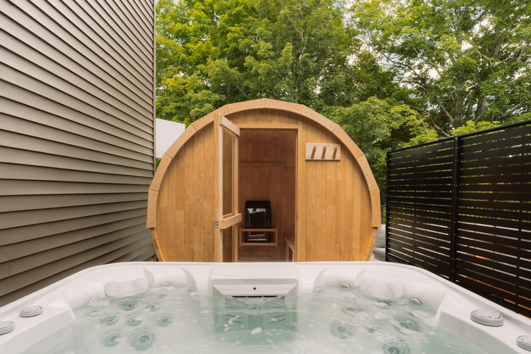 Cedar barrel sauna beside the outdoor hot tub on the deck