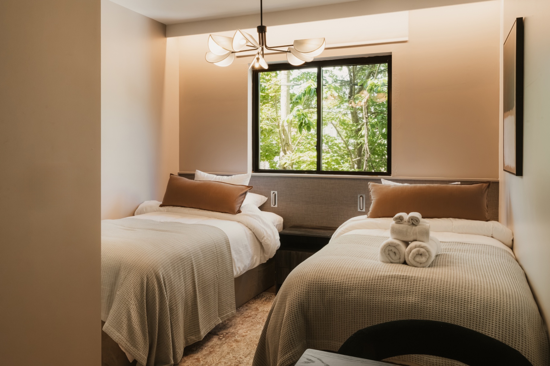 Twin beds with rolled towels beside a large window