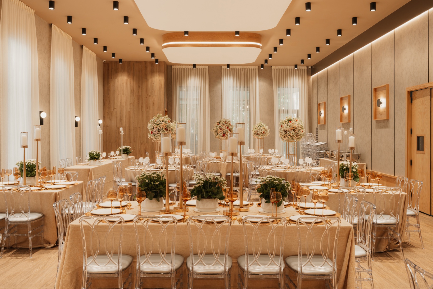 Banquet hall set for a celebration with a long head table and greenery