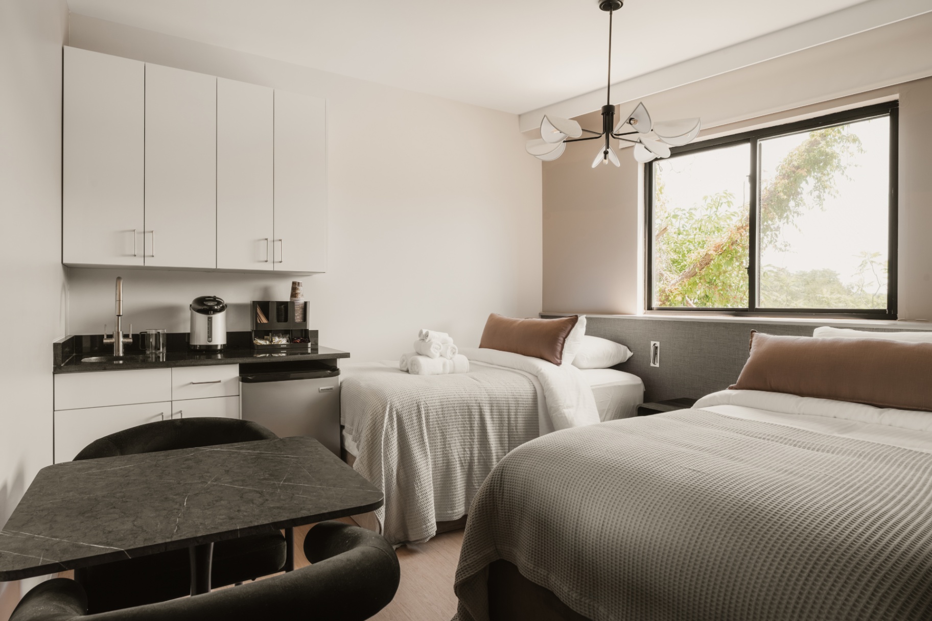 Guest room with beds, a kitchenette and a small round table