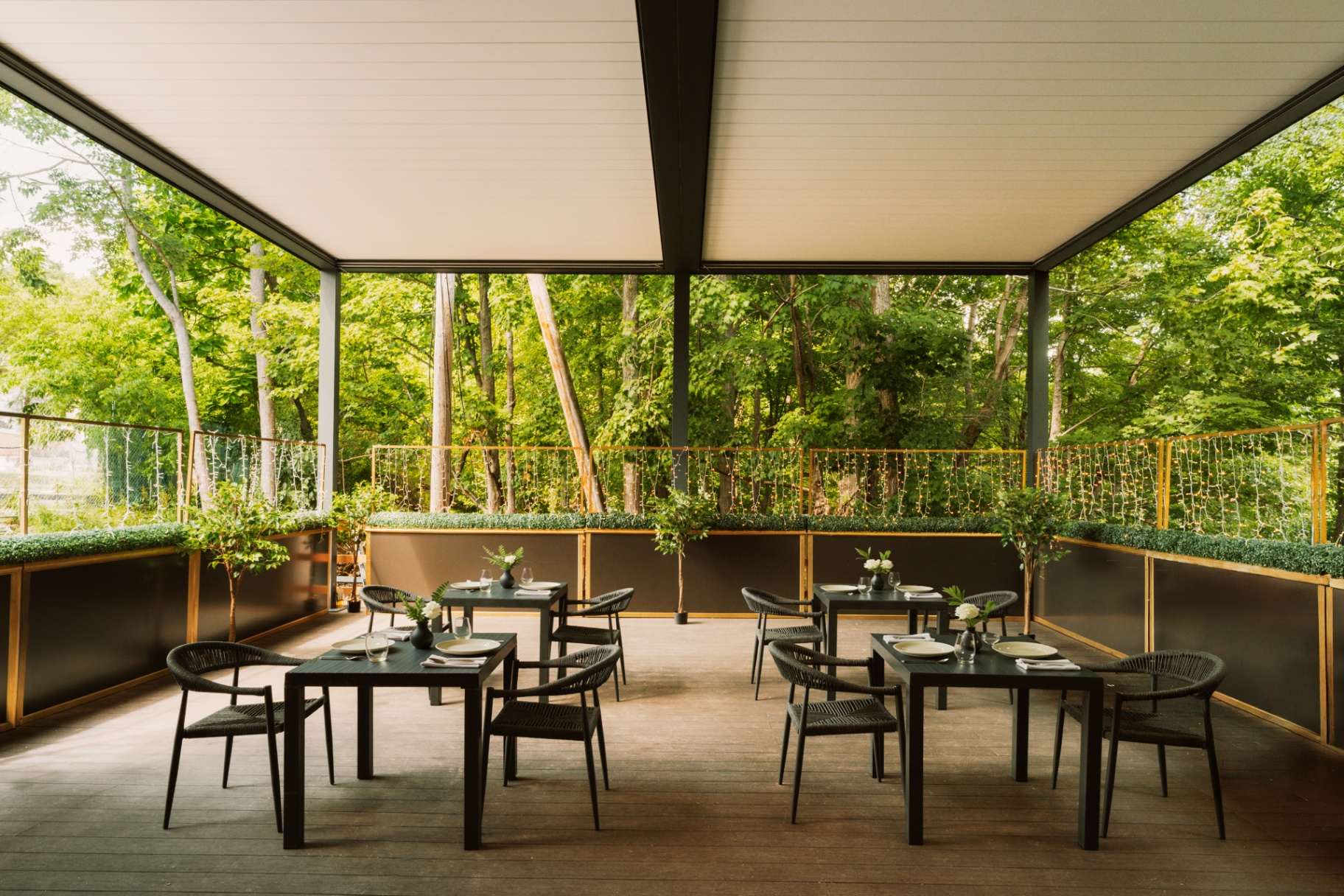 Covered pergola dining terrace with bistro tables and forest views