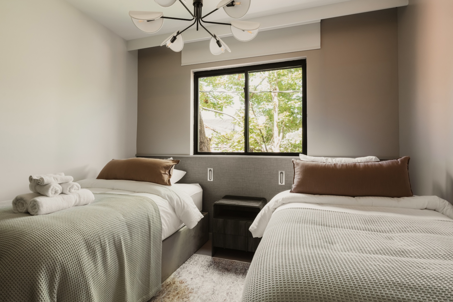 Guest room with two beds dressed in sage green blankets