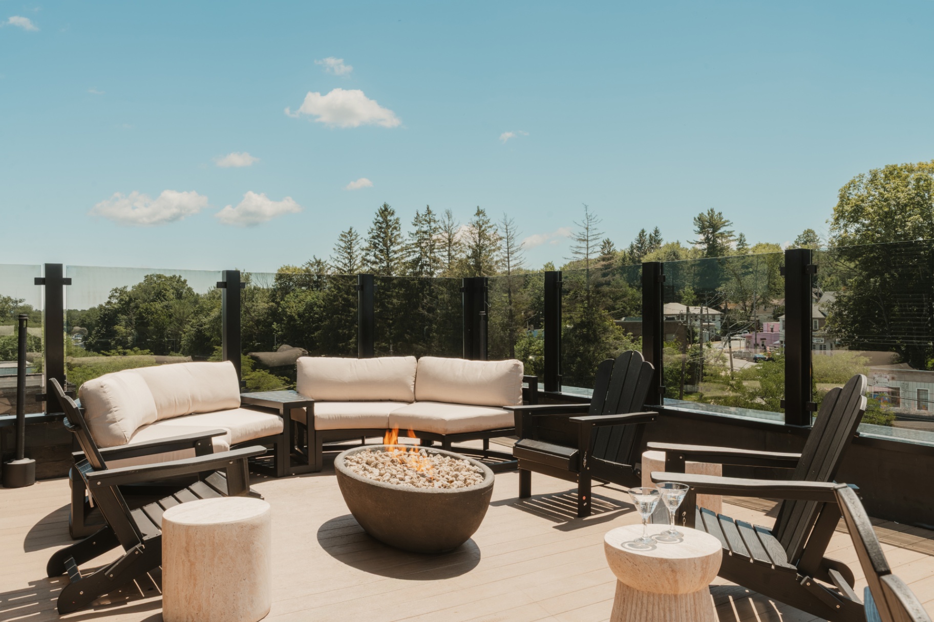 Outdoor lounge seating around a stone firepit overlooking the treeline