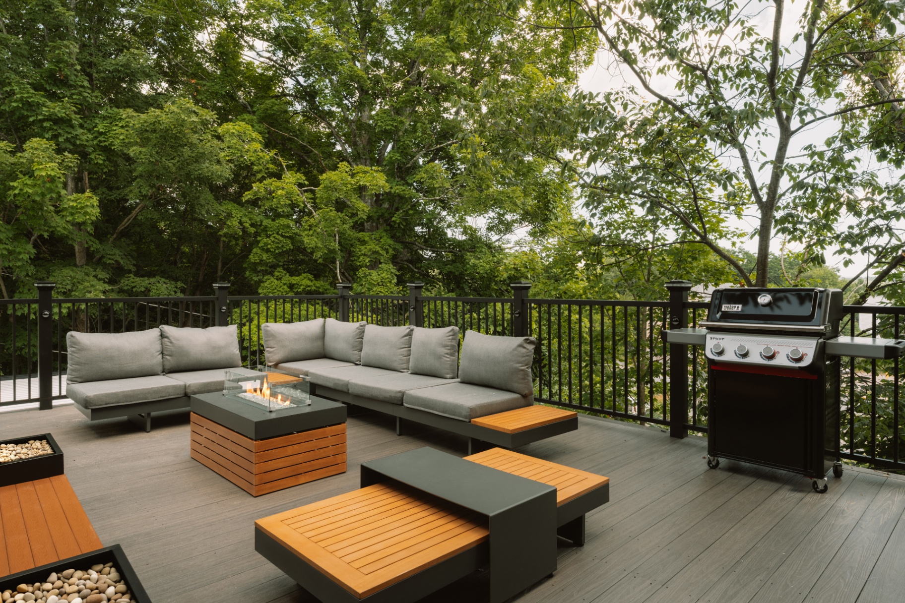 Outdoor deck lounge with a gas grill and firepit table