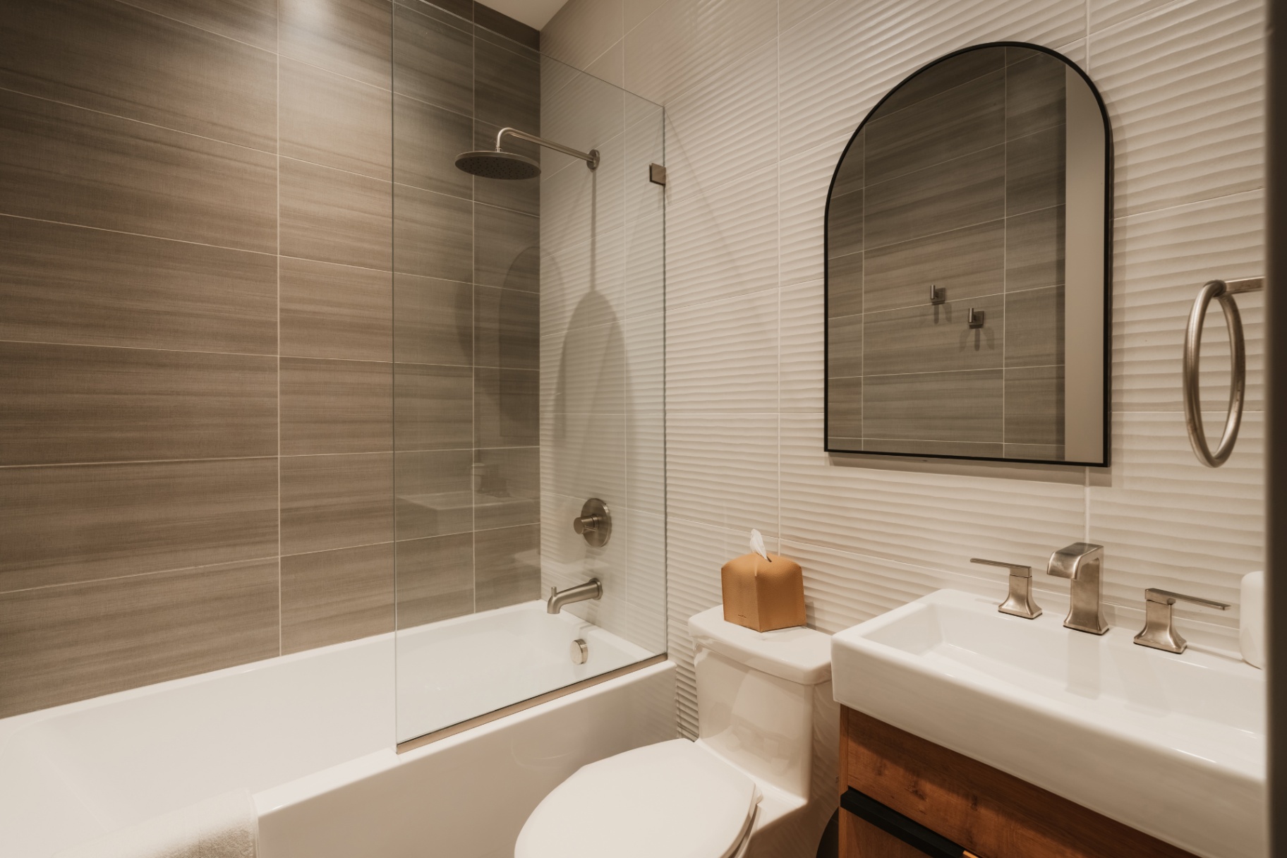 Bathroom with a shower-tub, arched mirror and vanity