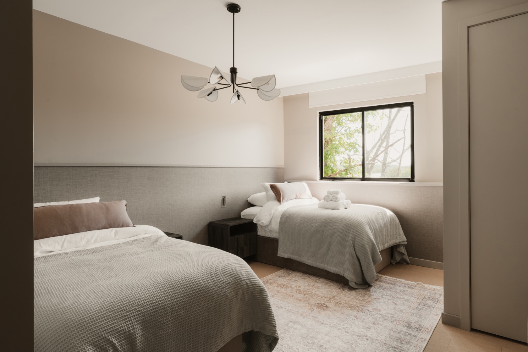 Guest room with two beds beneath a sculptural chandelier