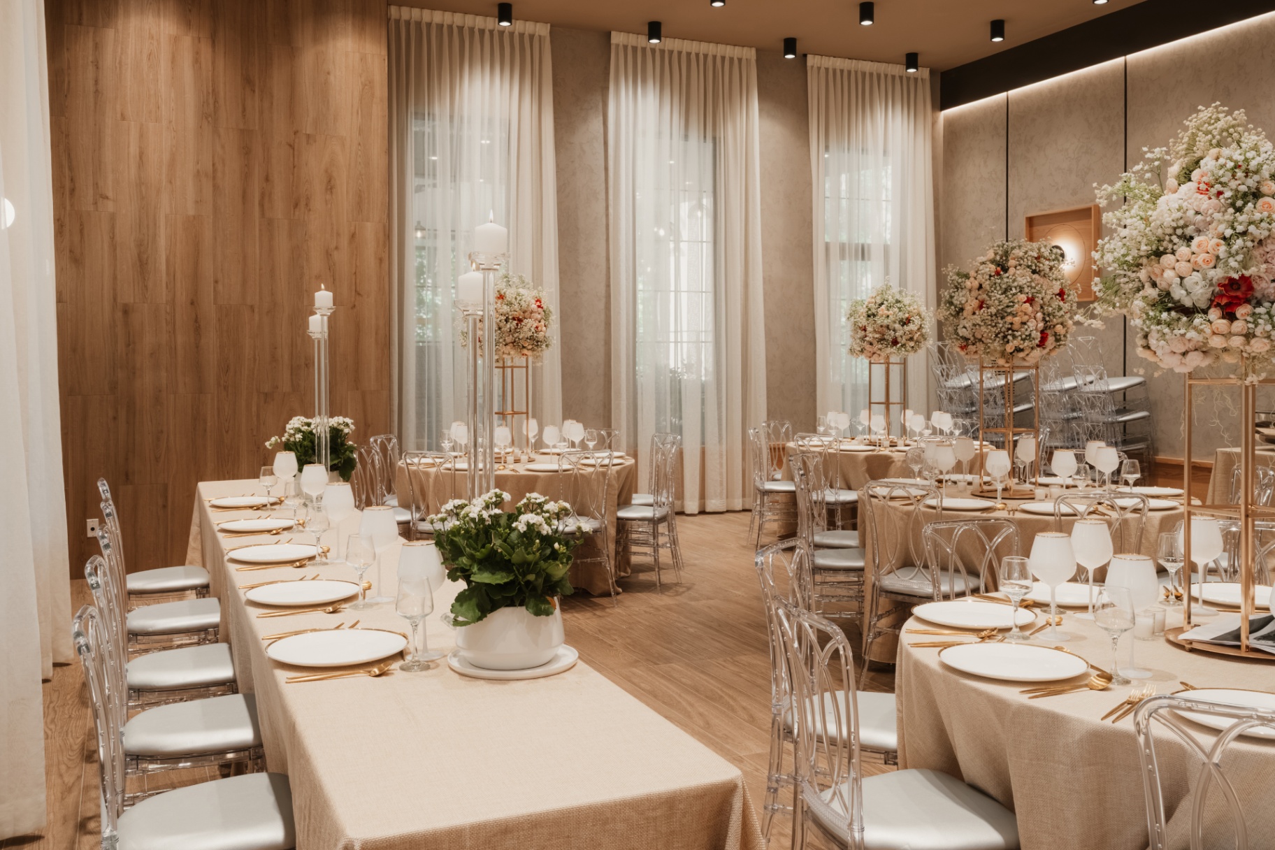 Long banquet table with white chairs and round tables in the event space