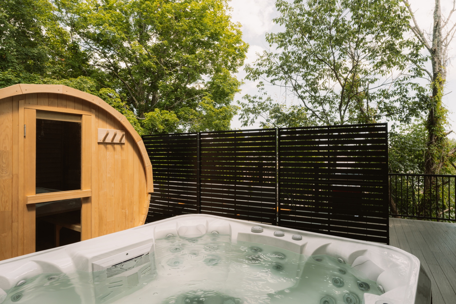 Bubbling outdoor hot tub with the barrel sauna in the background